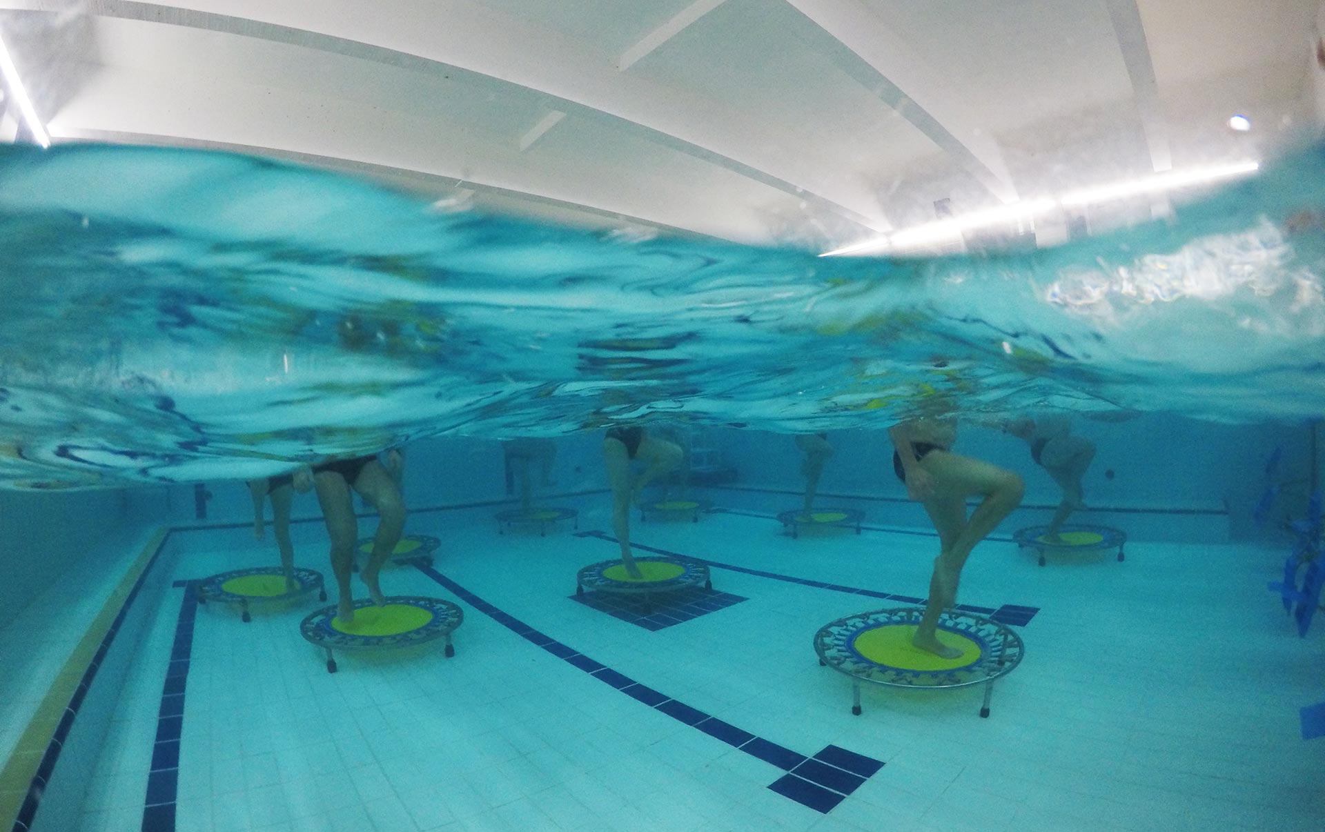 Vista subaquática de aula de hidrojump sobre camas elásticas na piscina