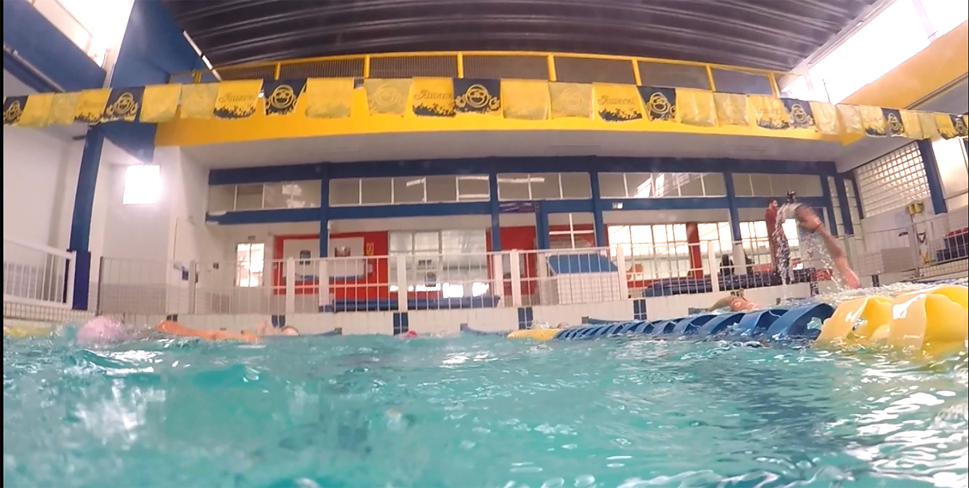 Vista de dentro da água da piscina 7, com bandeirolas da Amaral