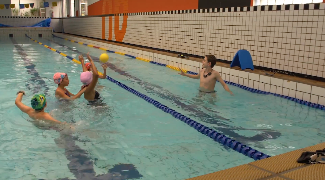 Crianças passando bola durante treino na piscina 6