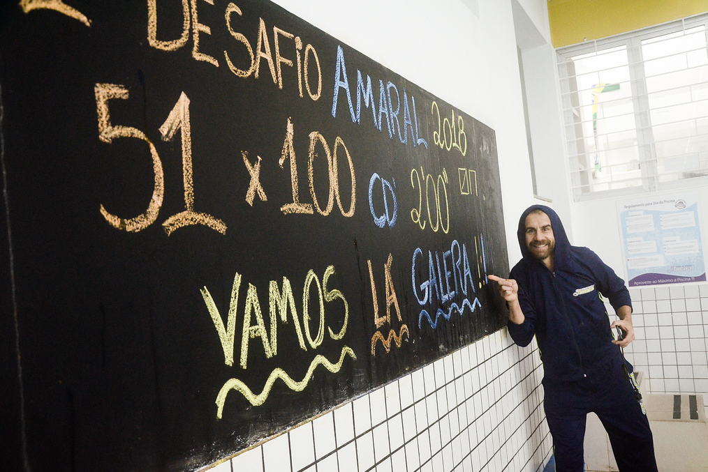 Professor ao lado do quadro do Desafio Amaral de 51 x 100 metros